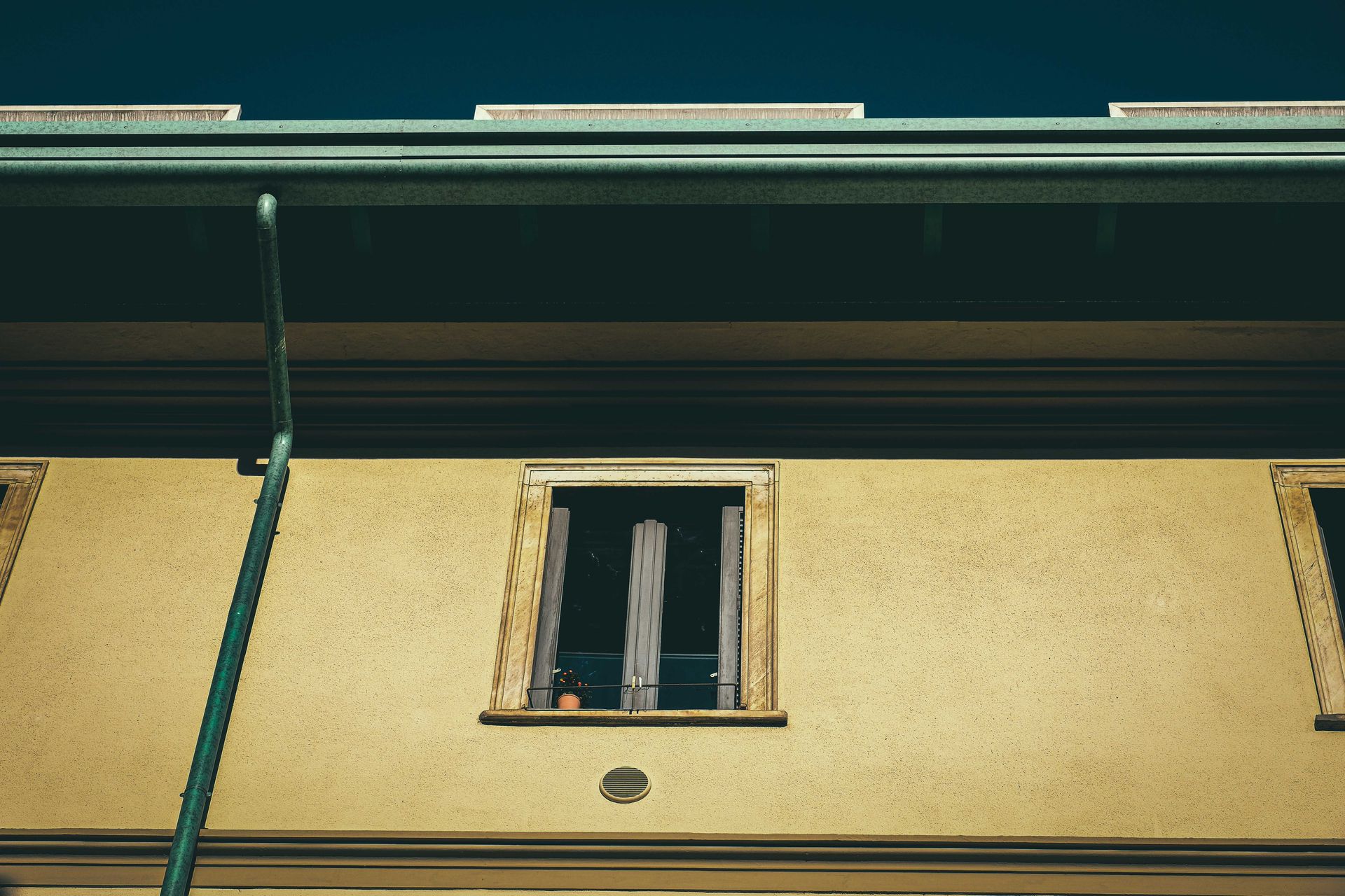 From below of aged dwelling building exterior with window on front wall in city in sunlight